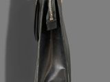 leather handbag hanging on a hook on a gray wall