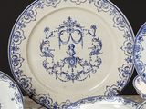 plusieurs assiettes bleues et blanches ornées d'un monogramme, posées sur une table