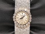 an image of a woman ' s watch sitting on a black leather bag