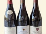 three bottles of wine are lined up on a white surface