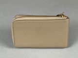 beige leather wallet with gold zipper on grey background