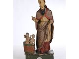une statue représentant un homme coiffé d'un chapeau et vêtu d'une robe, debout à côté d'une plante en pot