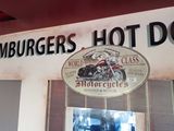 a sign that says hamburgers hot dog above a motorcycle