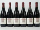 six bouteilles de vin rouge alignées sur une surface blanche