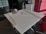 une table blanche sur laquelle est posé un ordinateur portable, dans une pièce