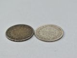 two coins sitting next to each other on a white surface