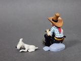 a small figurine of a man with a hat sitting on a rock next to a dog