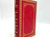 un vieux livre rouge posé sur une table, devant un fond blanc