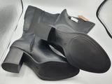 pair of black leather boots sitting on top of a white table