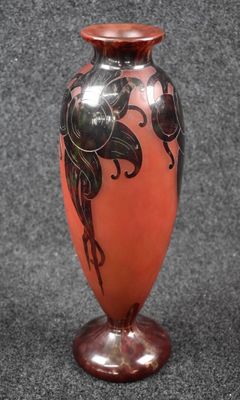 a red vase with black flowers on it on a gray surface