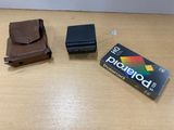 un appareil photo Polaroid posé sur une table à côté d'un portefeuille