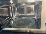 a silver microwave with a glass plate inside of it