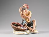 figurine représentant un homme assis sur un panier, tenant une bouteille de vin