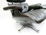 une image représentant un fauteuil et un repose-pieds en cuir noir sur fond blanc