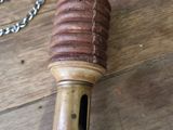 a wooden whistle with a chain around it on a wooden floor