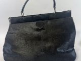 un gros plan d'un sac à main noir posé sur une surface blanche