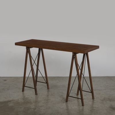 une photo d'une table en bois à deux pieds posée sur un sol en béton