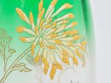 a green vase with a yellow and white flower on it