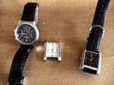 two watches sitting next to each other on a brown surface