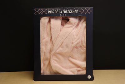 peignoir rose dans une boîte noire posée sur une table, sur fond noir
