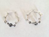 paire de boucles d'oreilles créoles en argent ornées de perles noires sur fond blanc