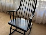 un fauteuil à bascule noir placé devant une fenêtre