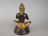 statue of a woman sitting on a rock with her legs crossed