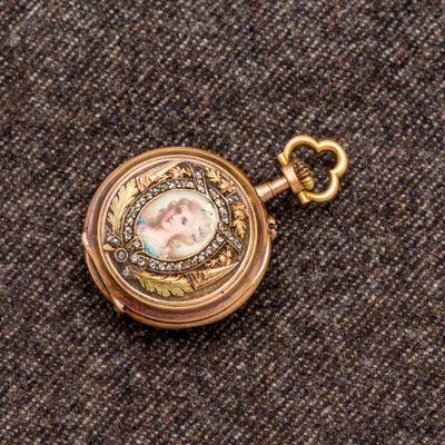 un gros plan d'une montre de poche en or sur laquelle figure le portrait d'une femme
