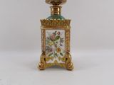 a small gold and green bottle with flowers on it