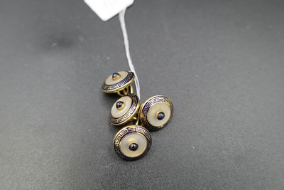 trois paires de boutons de manchette en or et émail noir sur un fond noir