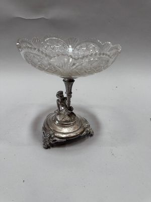 an antique silver plate with a glass bowl on top of it