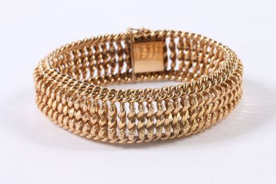 gros plan d'un bracelet en or sur fond blanc