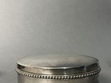 a silver box with a beaded lid sitting on a table
