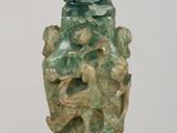 Vase chinois en jade vert sculpté, posé sur un socle, sur une table en bois