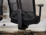 pair of black office chairs with arms and arms on casteors