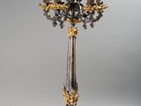 a tall gold and silver candle holder on a stand