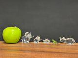 a green apple sitting on top of a wooden table next to a group of glass elephants