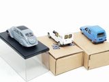 three toy cars sitting on top of boxes on a table