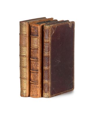trois vieux livres sont empilés sur une surface blanche