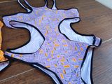purple and orange patterned swimsuit with black trimmings on wooden steps