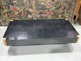 une boîte noire posée sur une table devant une tapisserie