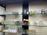 many glass jars and glasses on the shelves in the room