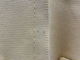 un gros plan sur un pull blanc orné d'un bouton bleu