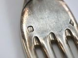 a close up of a silver fork with a diamond on it