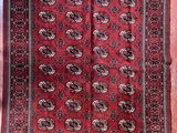 tapis oriental rouge et noir exposé dans une pièce