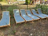 six chaises longues dans l'herbe, devant une clôture