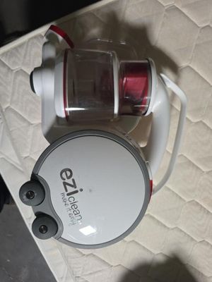 un aspirateur blanc et rouge posé sur un lit, muni d'un cordon rouge