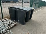 a black trash can sitting on the side of the road