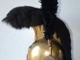a gold helmet with a black feather on it