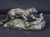 bronze sculpture of a tiger on a rock on a black background
